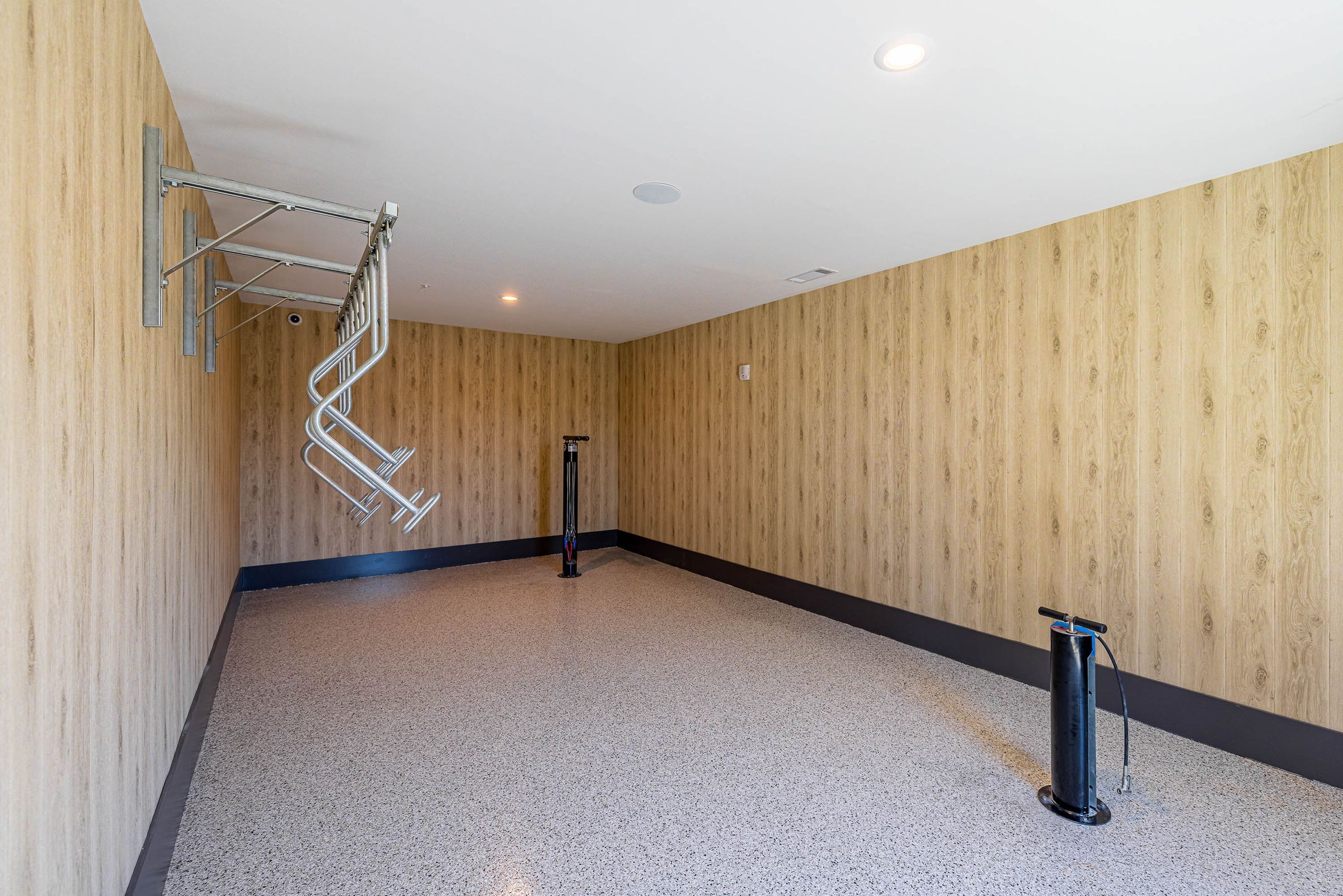 Botanic Luxury Apartments Empty room with wooden paneled walls, ceiling light, and metallic bike racks on one side.