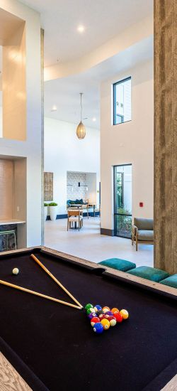 Botanic Luxury Apartments Spacious modern game room with a pool table, TV, high ceilings, large windows, and stylish lighting fixtures.