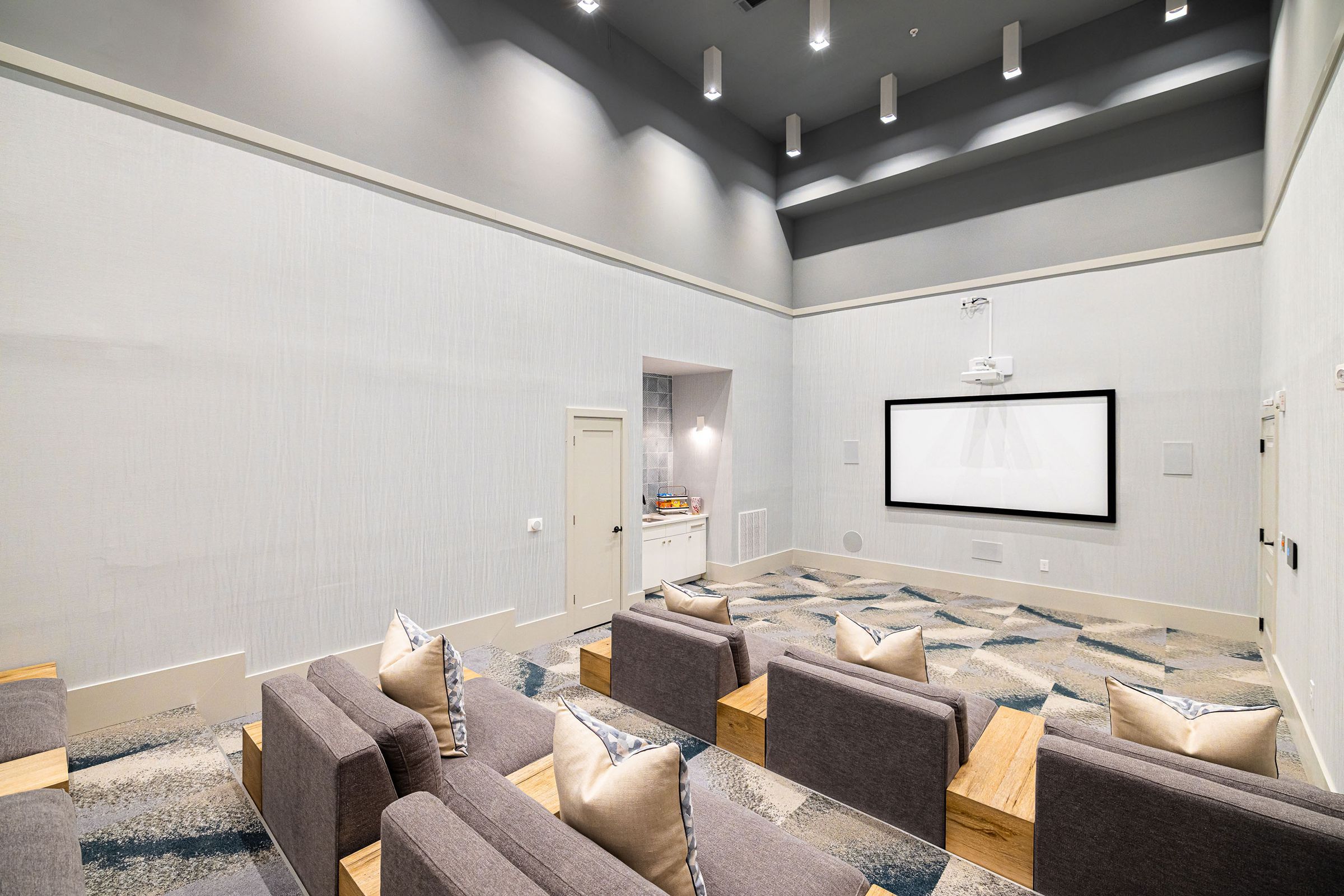 Botanic Luxury Apartments Theater room with rows of seats facing a large projector screen.